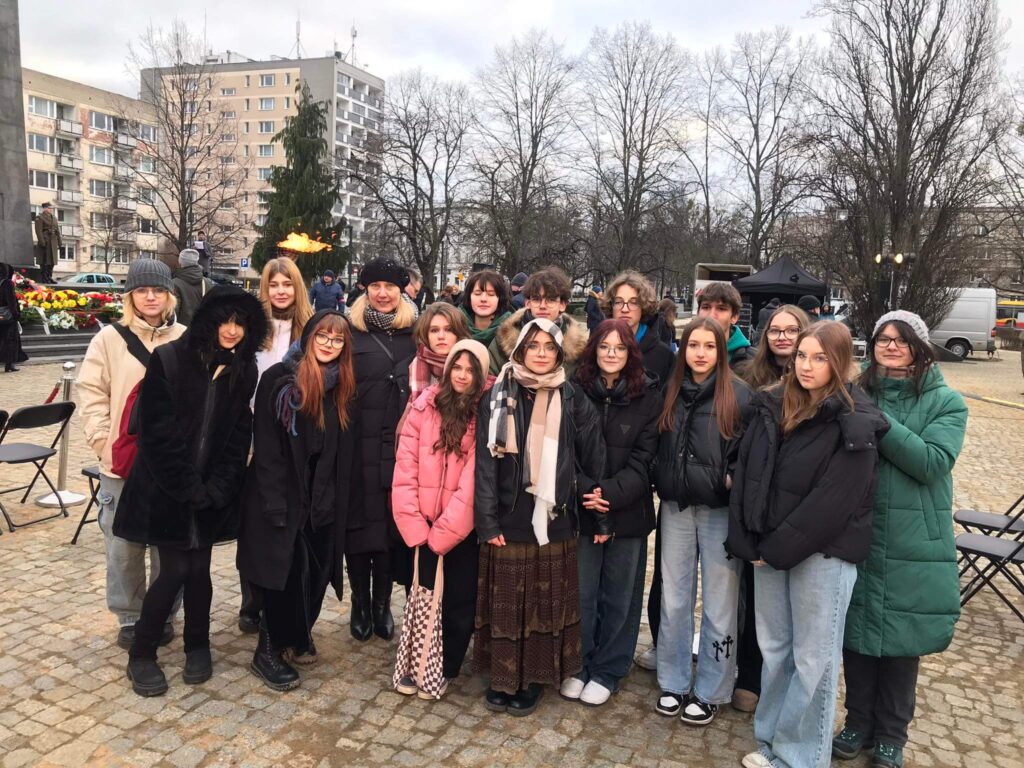 Uczniowie stojący przy pomniku holokaustu